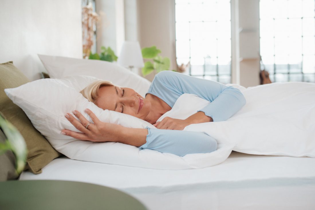 Frau schläft erholsam im Bett