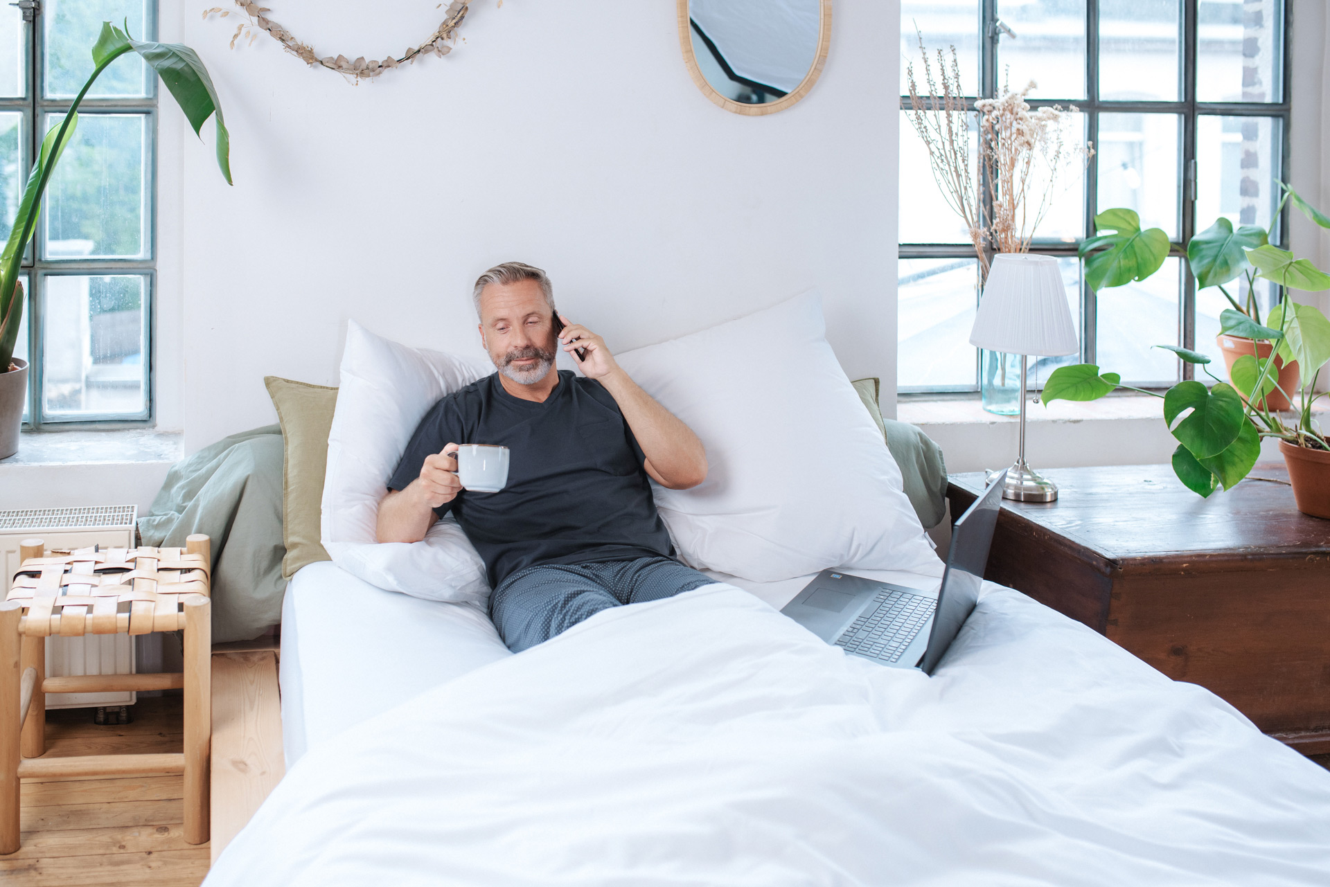 Mann im Bett nimmt telefonisch Kontakt auf